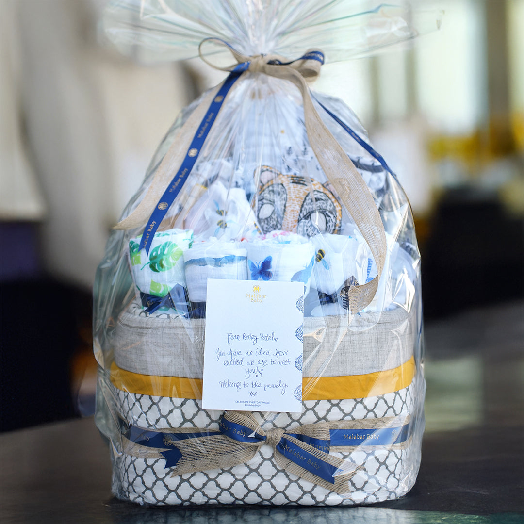 Premium Malabar Baby gift hamper with eco-friendly baby clothing, soft towels, and a cuddly plush toy.