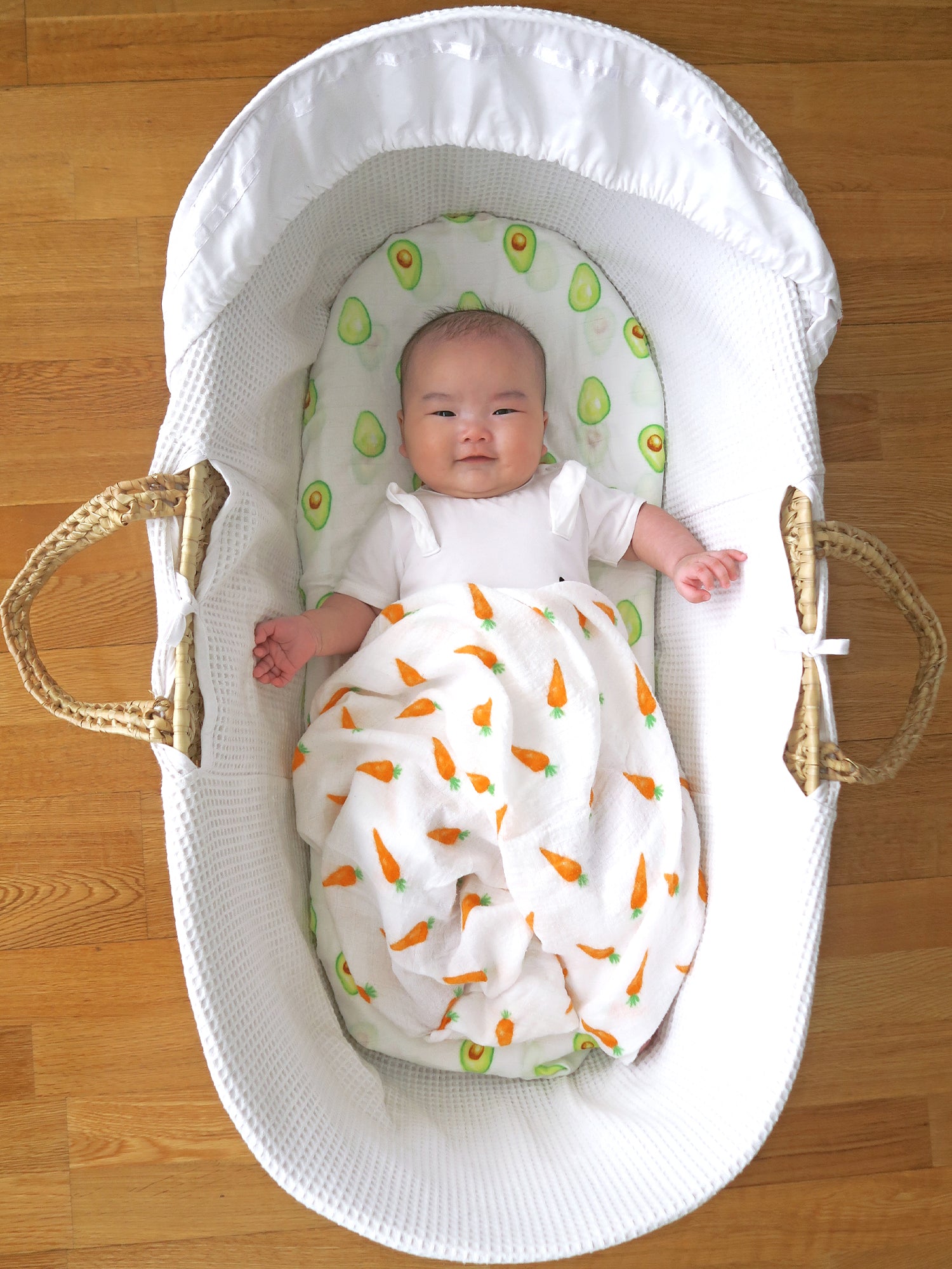 Organic muslin swaddle featuring a charming carrot and avocado print, made from soft, breathable fabric perfect for soothing and comforting a baby's delicate skin. Ideal for new parents seeking gentle, safe, and stylish baby swaddle options.
